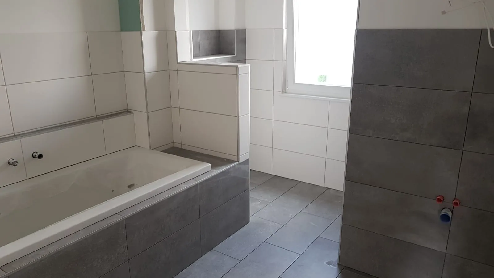 Modernes Bad mit Wanne und großformatigen Fliesen